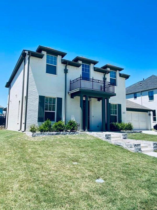 a white house with green shutters and a balcony