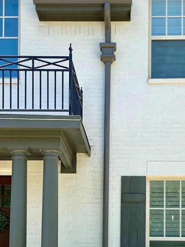 a white brick house with a balcony and a black railing .