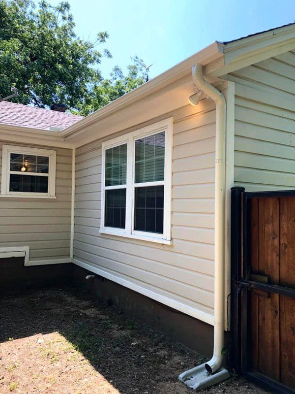 the side of a house with a gutter and two windows .