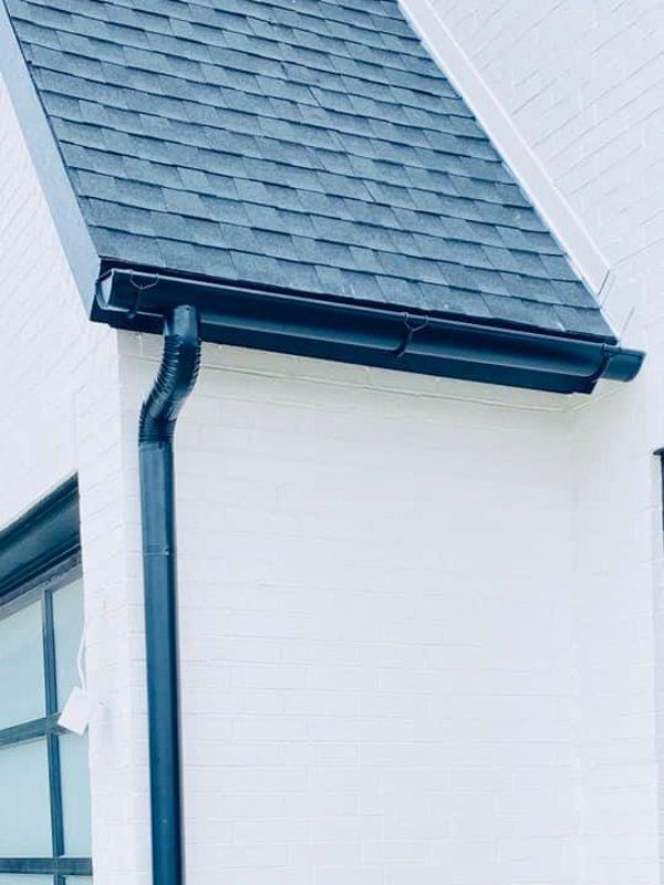 a white house with a black gutter and a black roof .