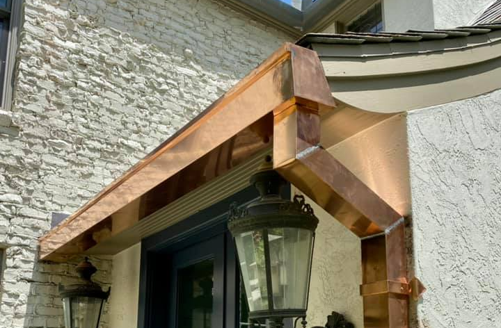 a house with a copper awning over the door and a lamp on the porch .