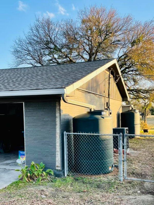a house with a chain link fence and water tanks in front of it .