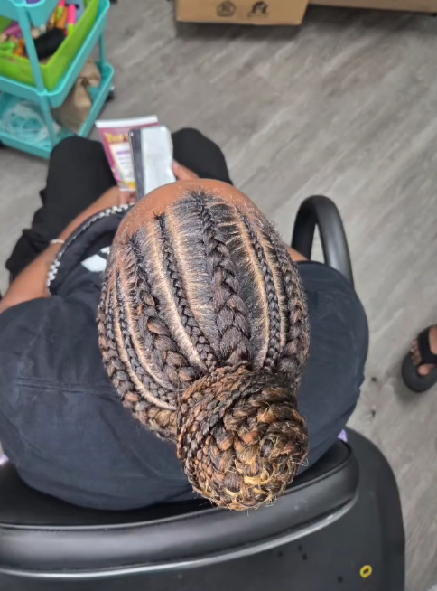 Person with braided hair, bun in a salon chair. Braids are light brown and dark brown.