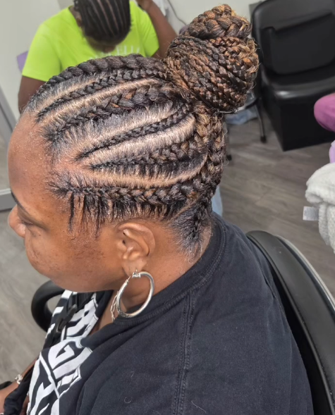 Woman with braided hair styled in a bun. Braids are light brown, wearing large hoop earrings, and black top.