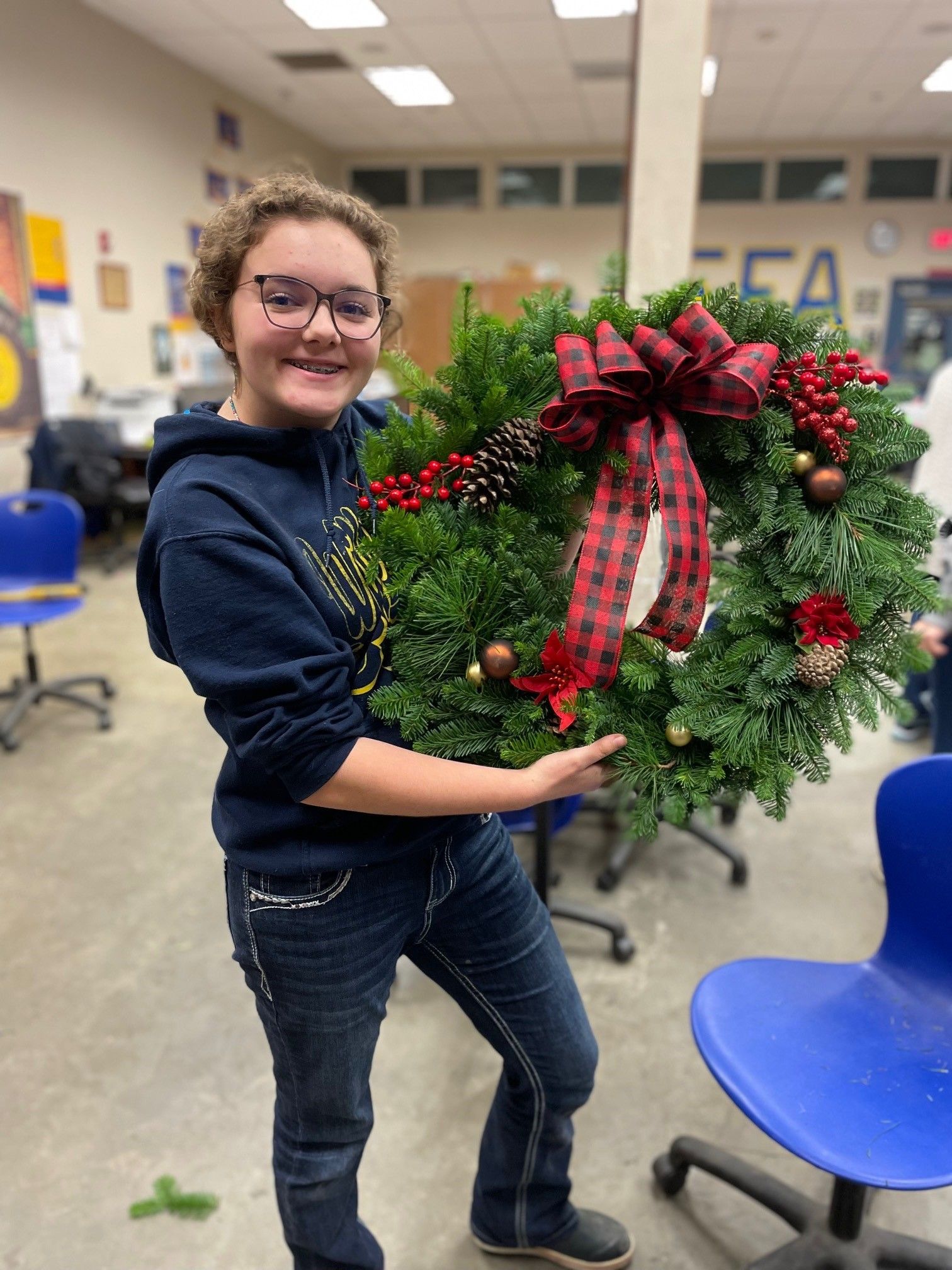 A young girl is holding a christmas wreath in her hands.