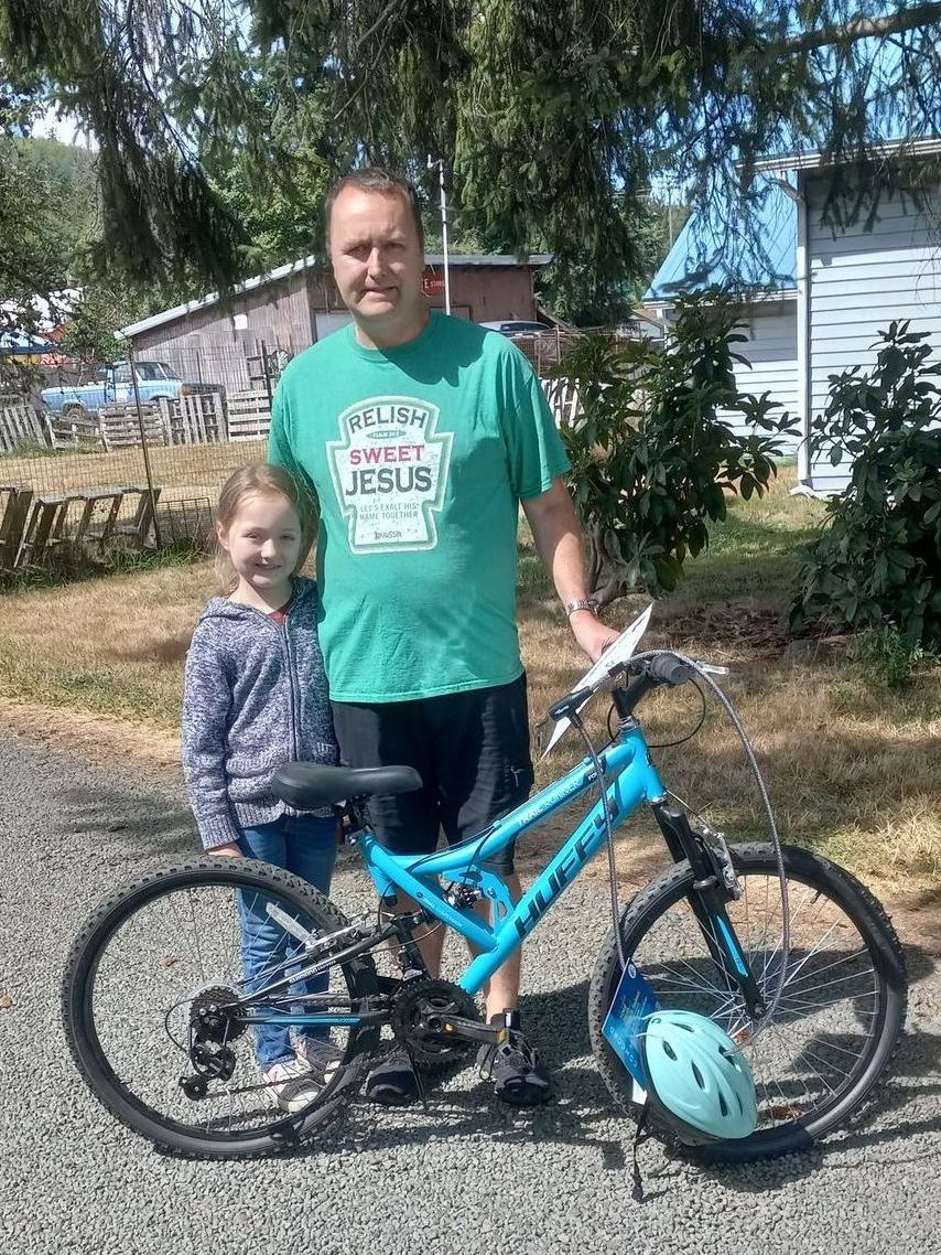 A man and a little girl are standing next to a bicycle.