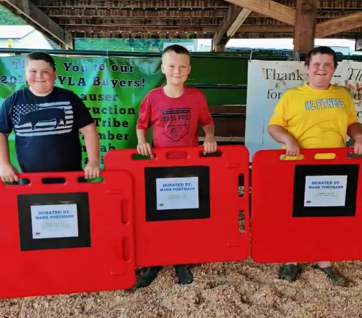 Three boys are holding red barriers in front of a sign that says thank you for your buyers