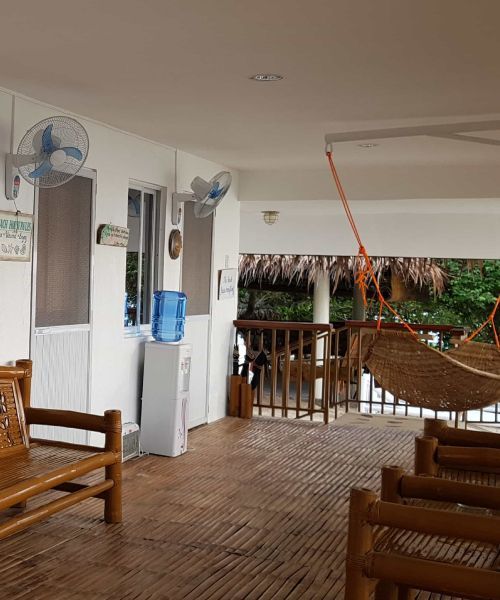 Covered porch with bamboo benches, fans, water dispenser, and hammock.