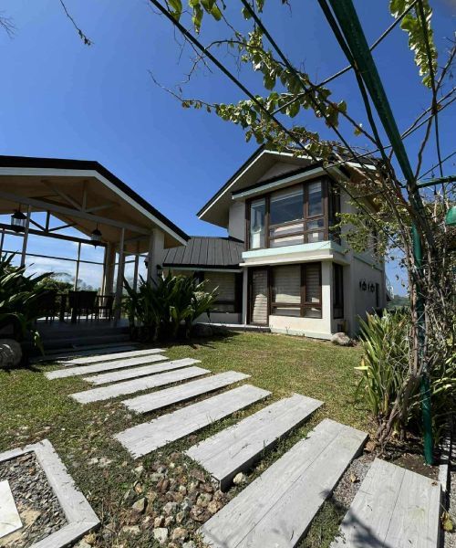 A two-story house with a pathway to a covered patio on a sunny day.