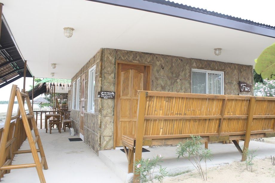 A waterfront cabin with a bamboo fence, porch, and a wooden door.