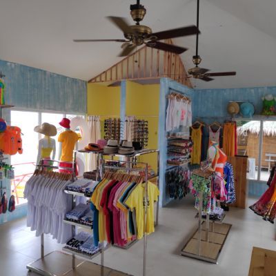Clothing store interior with colorful shirts, displays, and ceiling fans.
