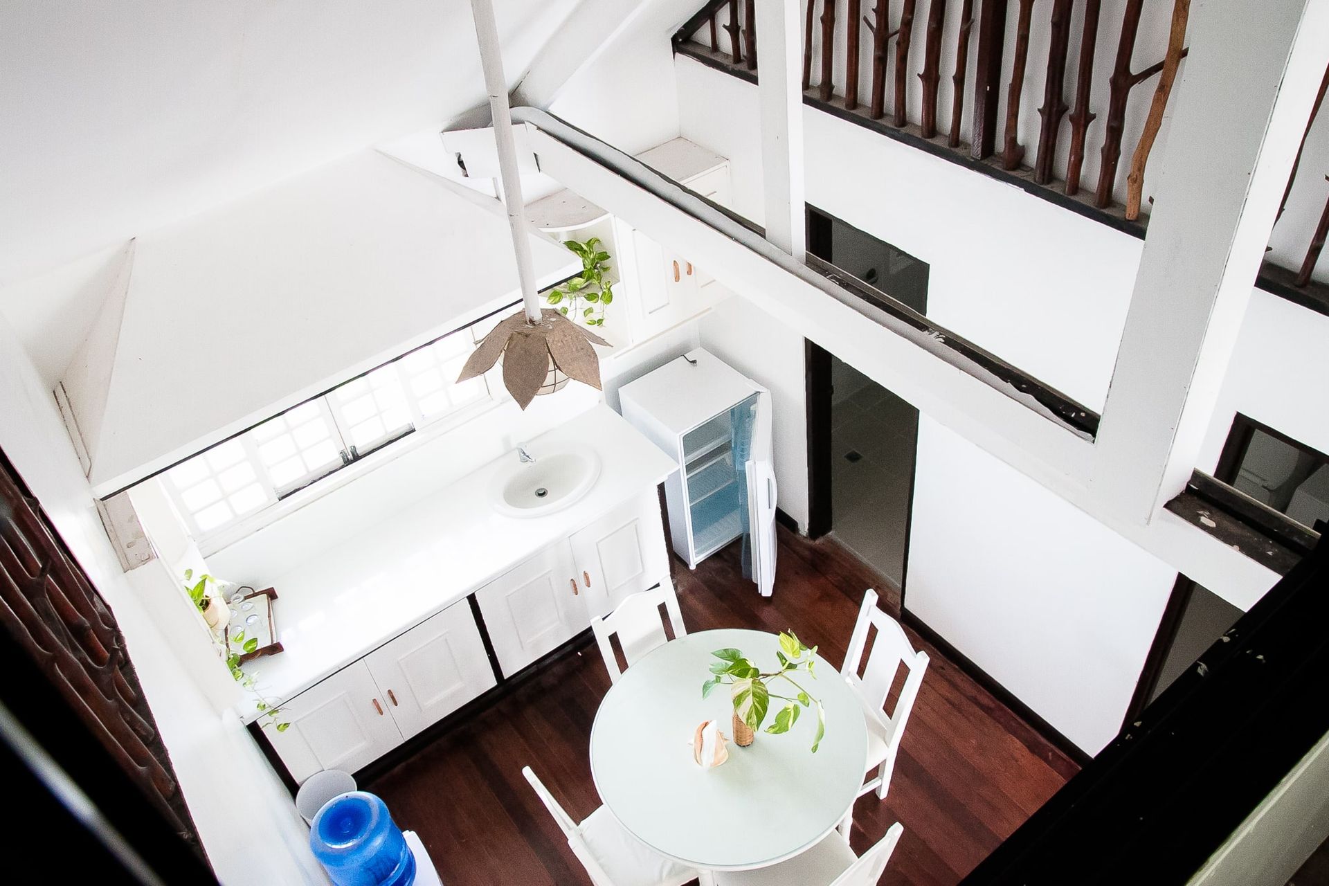Overhead view of a bright, white kitchen and dining area with a round table, cabinets, and a balcony.