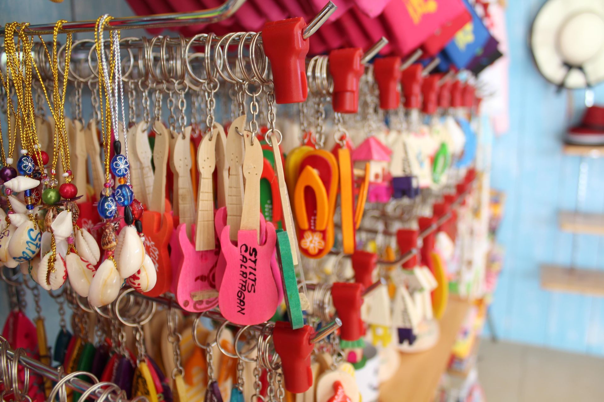 Keychains displayed in a shop, featuring shells, guitars, sandals, and other colorful souvenirs.