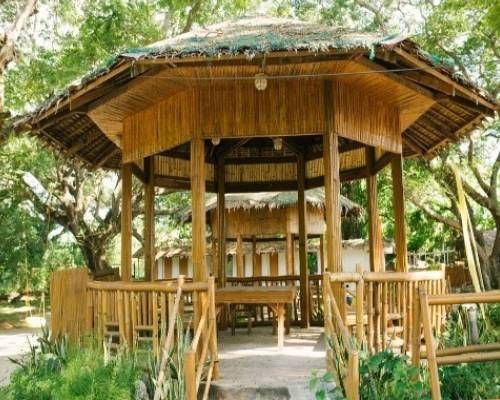 Bamboo gazebo with thatched roof in a natural outdoor setting.