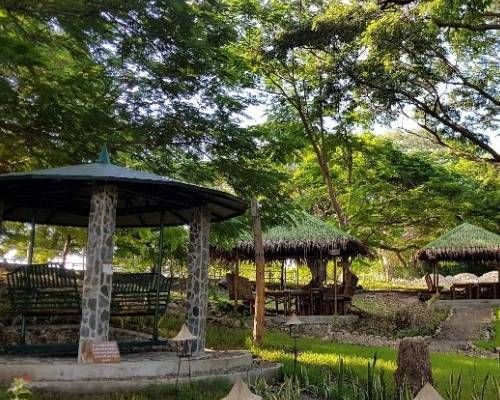 Gazebos in a park setting, surrounded by trees and greenery.