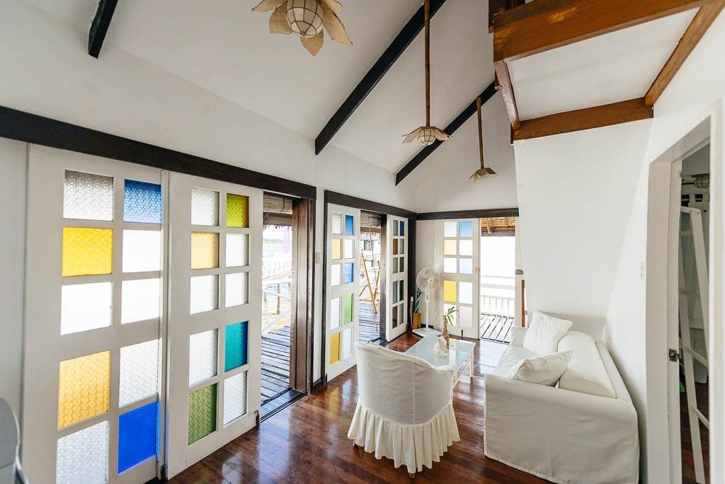 Bright living room with stained glass doors, white sofa, and wood floors.