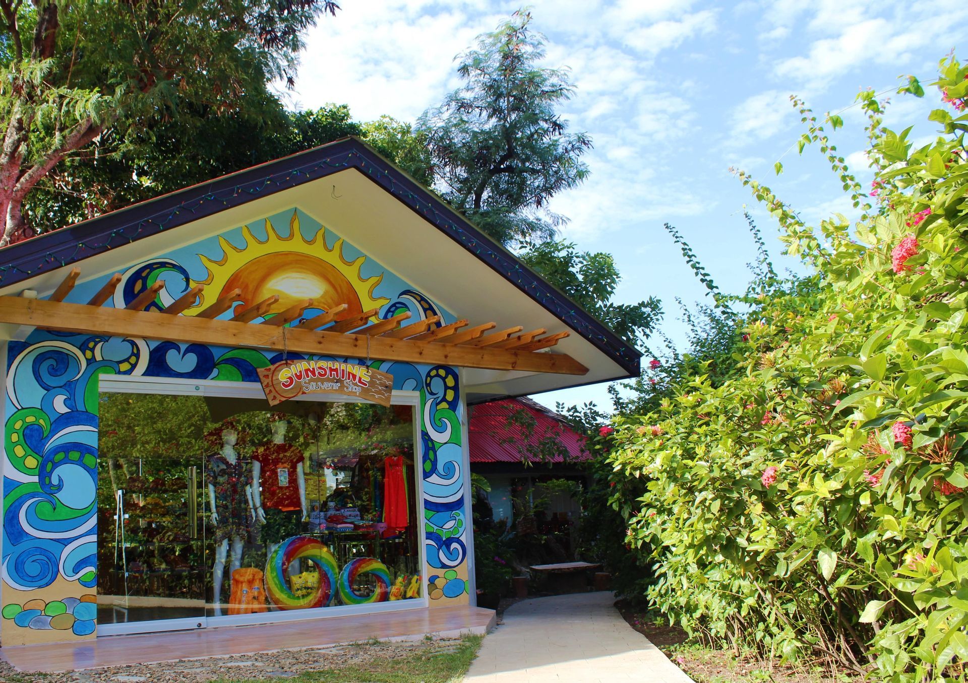 Colorful art pavilion entrance with glass windows, pathway, and lush greenery.