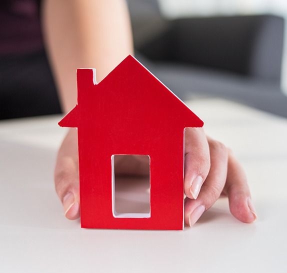 A woman is holding a small red house in her hands.
