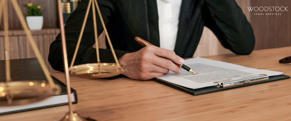 Lawyer reviewing legal documents with scales of justice on desk – Woodstock Legal Services