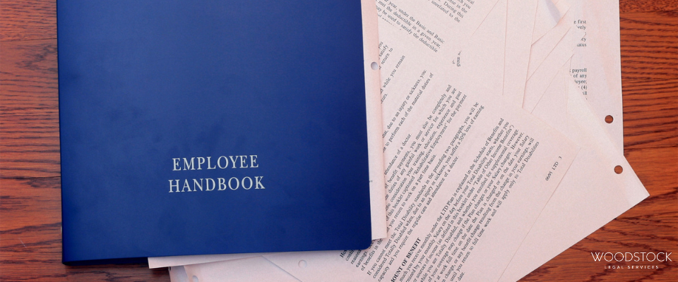 Blue employee handbook folder placed on top of printed documents on a wooden desk