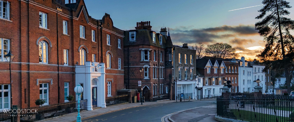 Red-brick historic buildings along a curved street at sunset, with Woodstock Legal Services