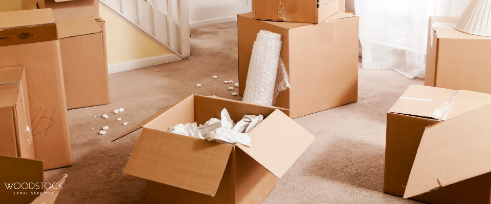 Cardboard moving boxes scattered around a carpeted room, some open with packing paper and bubblewrap