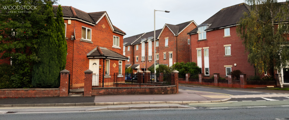 A row of modern red-brick residential houses with pitched roofs, front gardens, and low brick walls