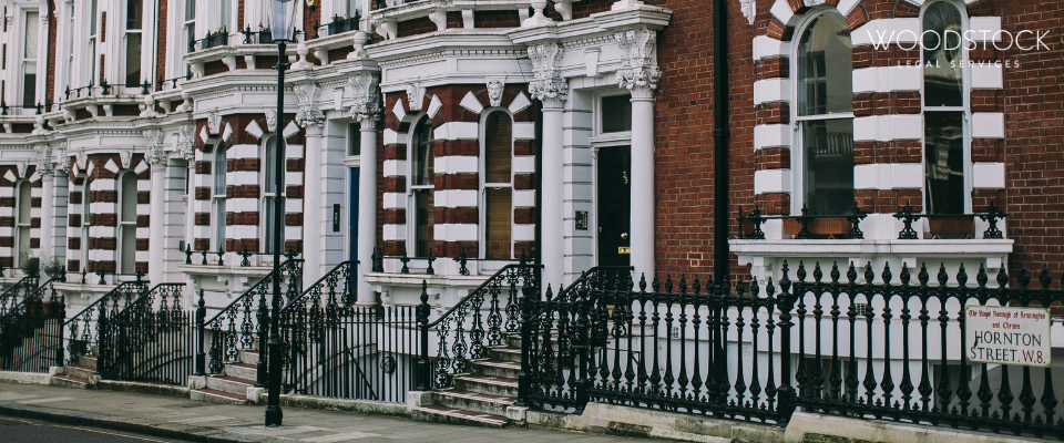 Row of traditional London terraced houses with black railings and red brick facades, representing UK