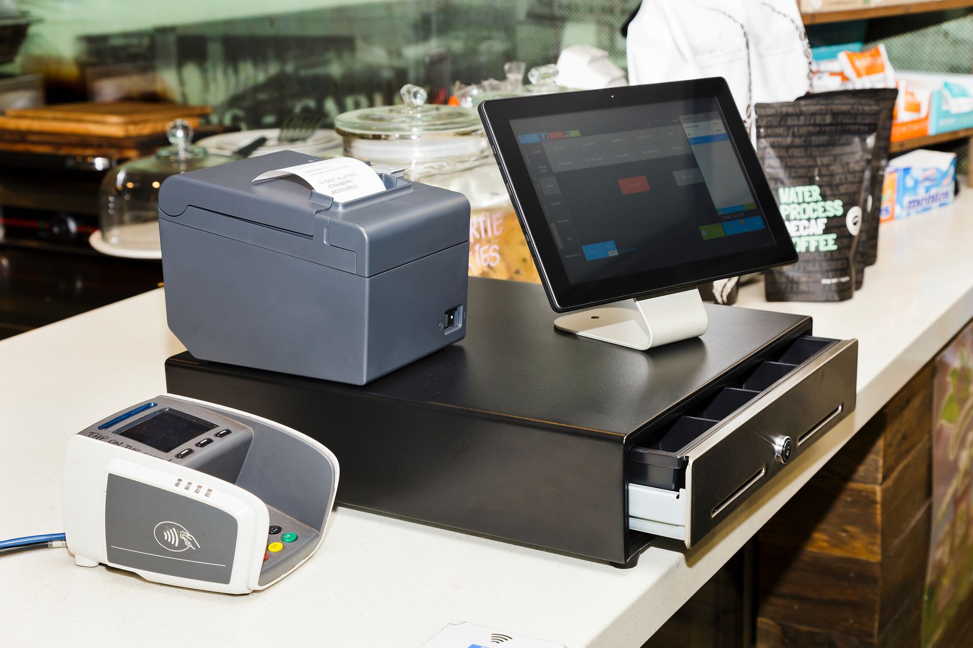 Restaurant checkout counter with a touchscreen POS terminal, receipt printer, and card reader