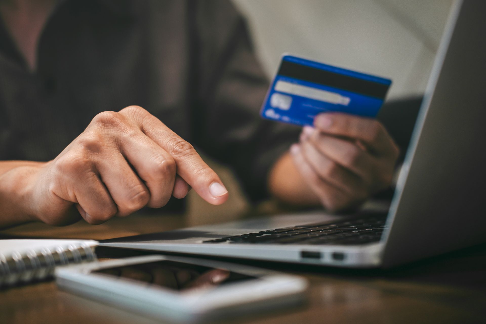 Hands using a credit card and laptop for online shopping on a desk
