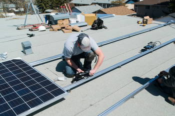 A man is installing solar panels on the roof of a building