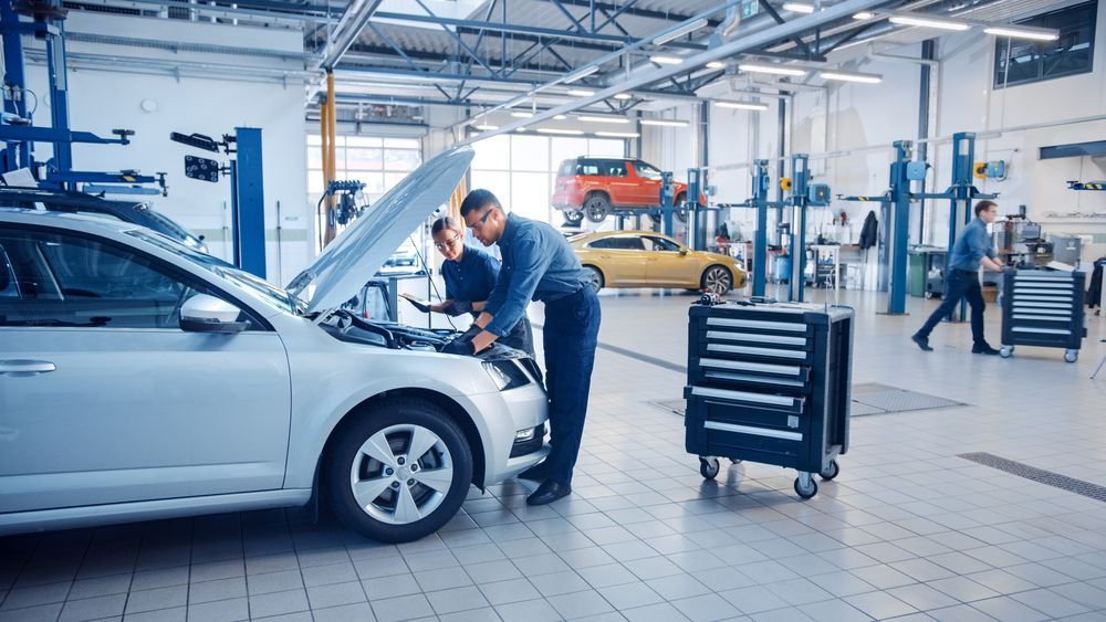Two Mechanics Working on a Car in a Brightly Lit Auto Repair Shop — Argenton Automotive Repairs In Boolaroo, NSW