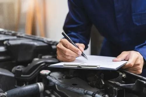 Mechanic in Blue Coveralls Inspecting a Car Engine, Writing on a Clipboard — Argenton Automotive Repairs In Boolaroo, NSW