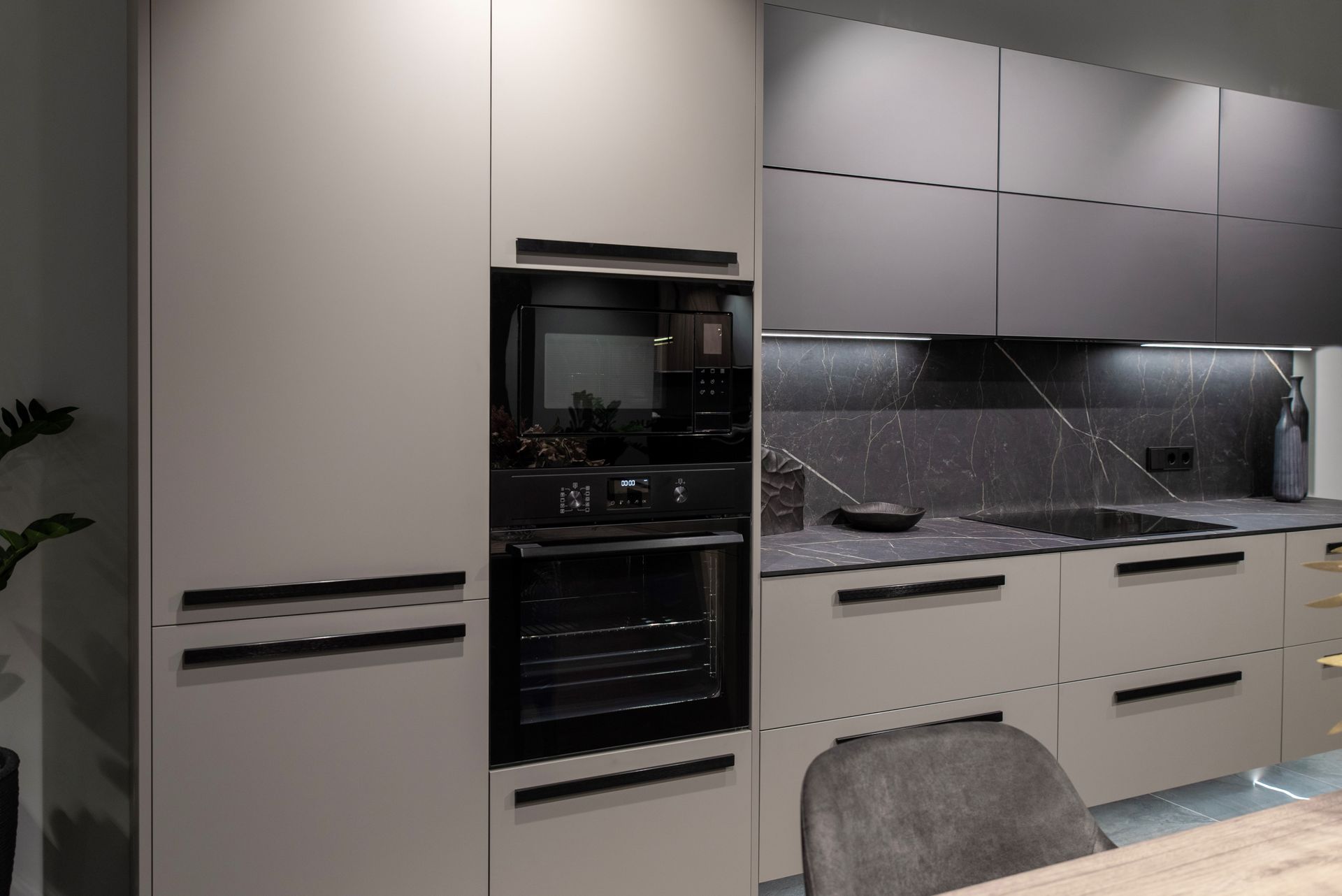 Modern kitchen featuring matte light grey cabinets, dark charcoal upper units, a wall oven, and marble-look countertops.