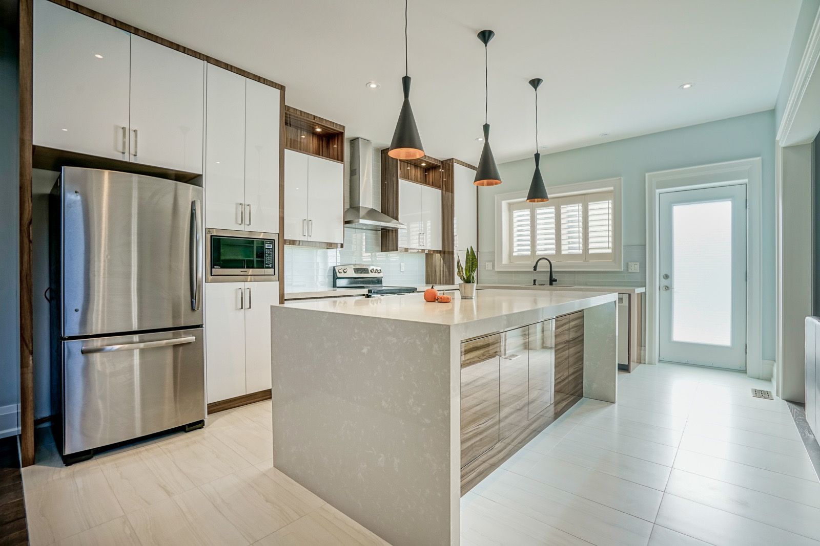 A kitchen with stainless steel appliances , white cabinets , and a large island.