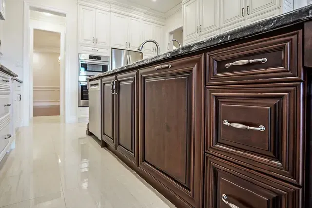 Kitchen island with dark brown cabinets, granite countertop, and stainless steel hardware.