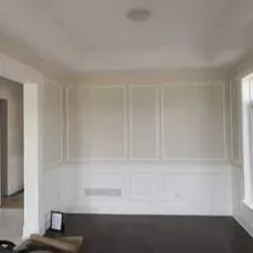 Empty room with white paneled walls, dark floor, and white ceiling.