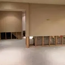 Interior view of a room with exposed wall studs; drywall removed from bottom section of walls.