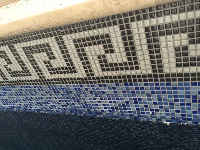 Poolside with blue and white mosaic tiles, featuring a Greek key pattern and dark blue water.