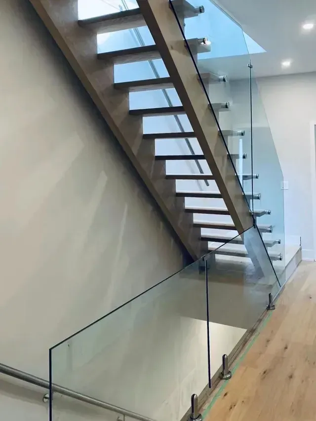 Wooden staircase with glass railing. Light wood steps, modern design, stainless steel hardware.