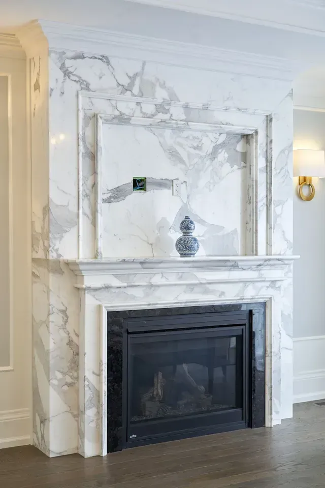 Marble fireplace with built-in hearth, a small alcove, and a dark, framed firebox.