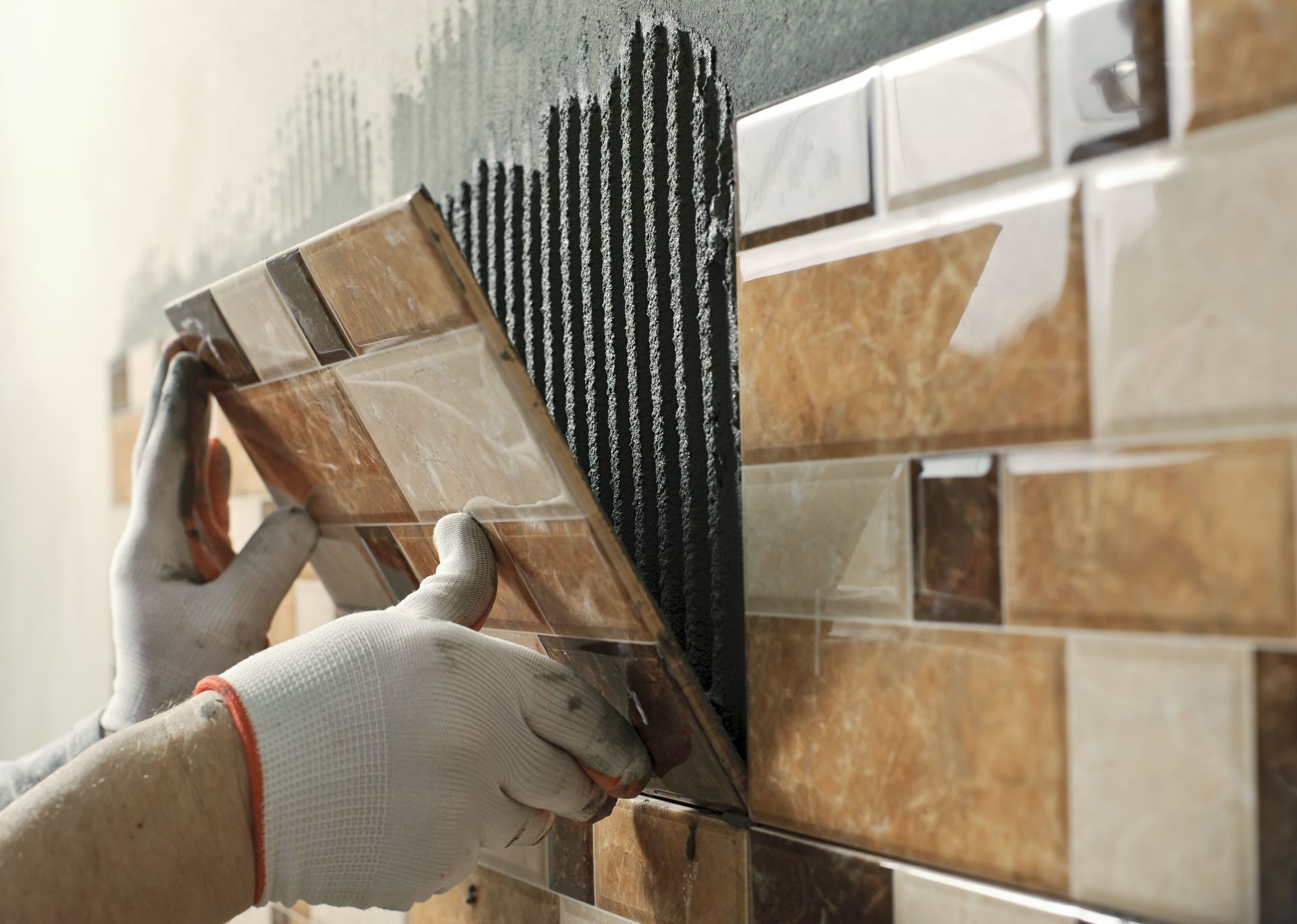 A person is installing tiles on a wall.