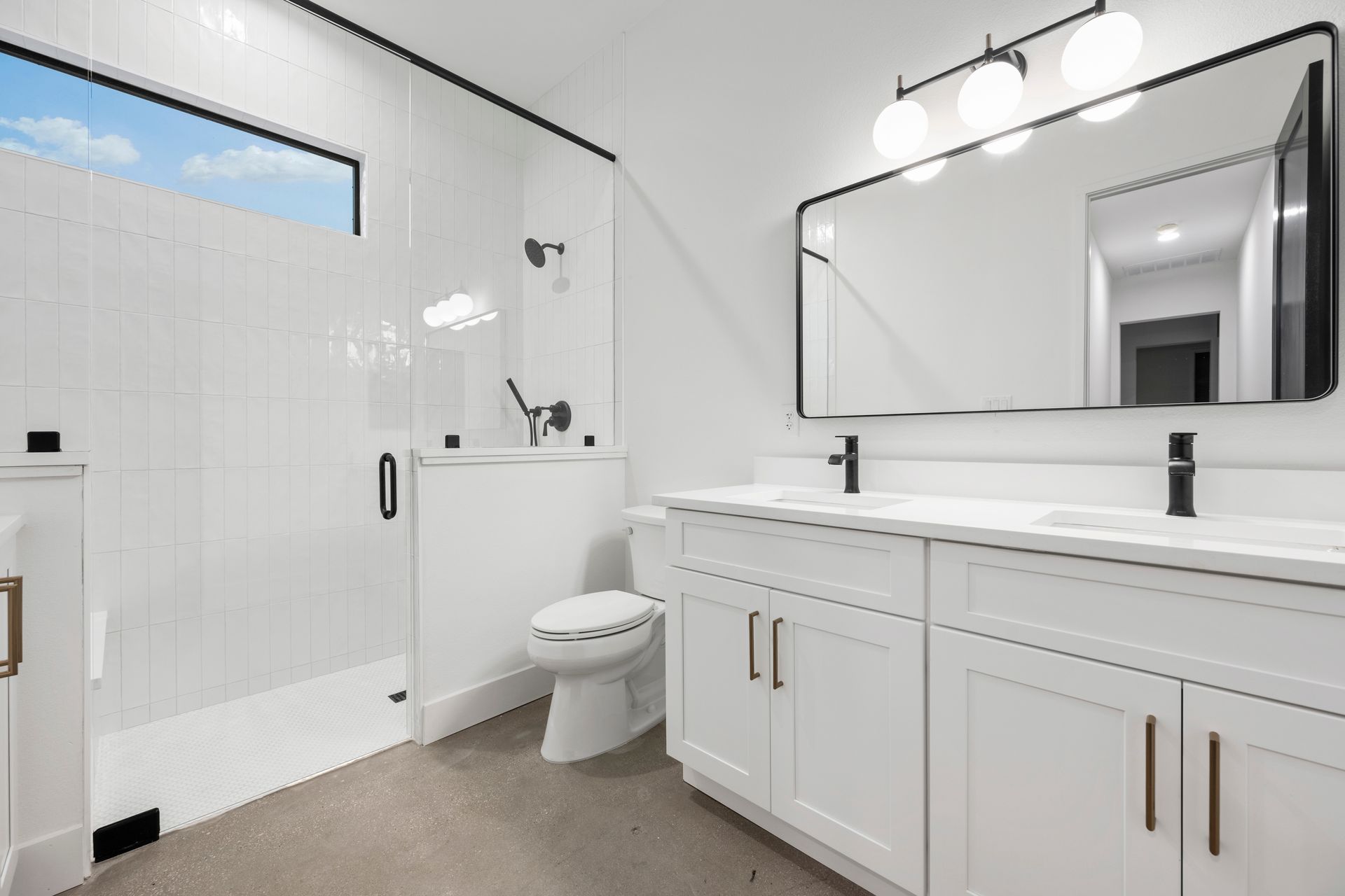 Modern white bathroom with a shower, double vanity, and a large mirror.