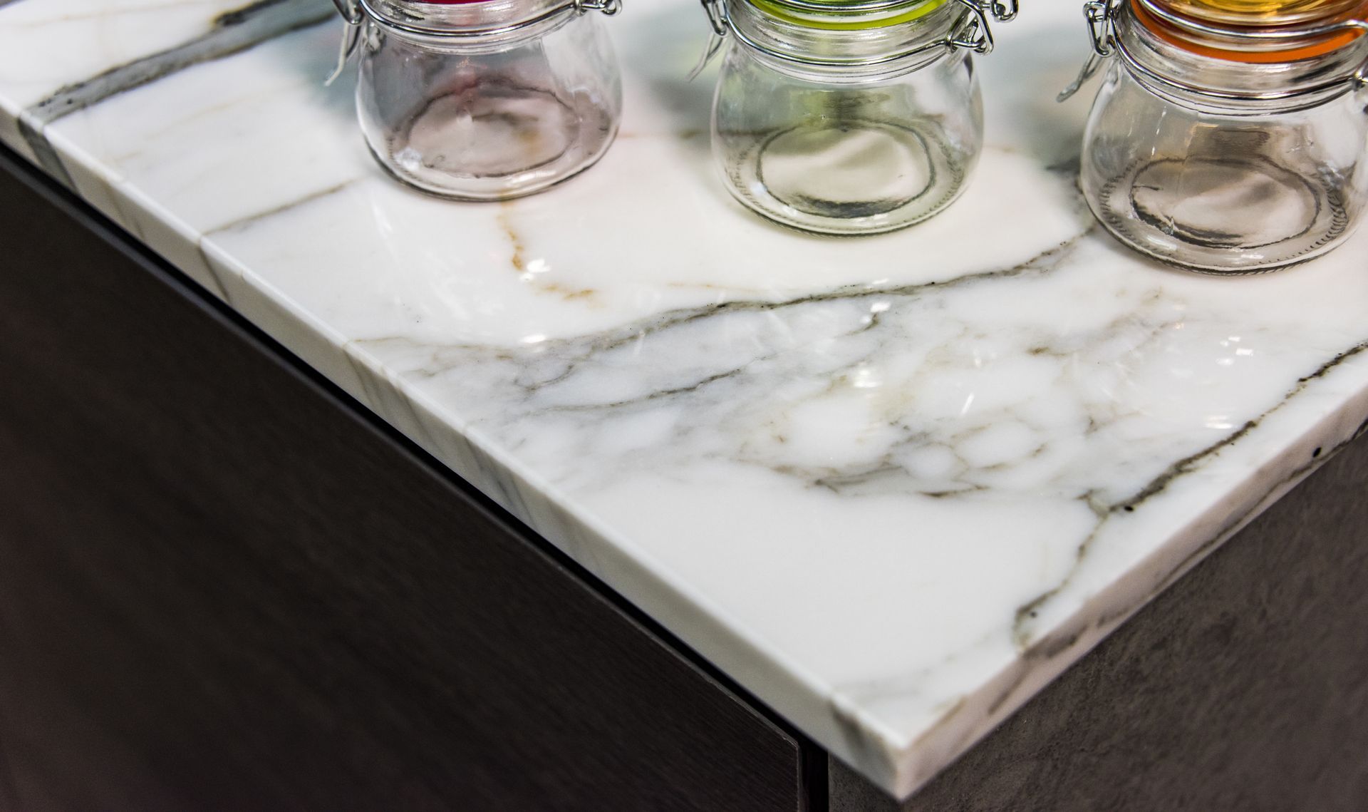 Three jars are sitting on a marble counter top.