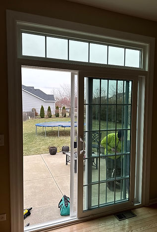 A man is working on a sliding glass door in a living room.