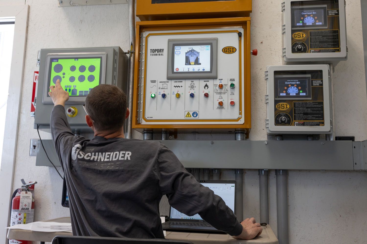 A man wearing a schneider shirt is working on a computer