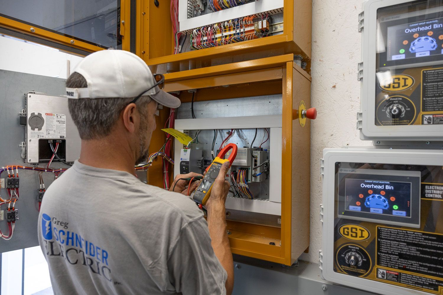A man is working on an electrical panel with a multimeter.