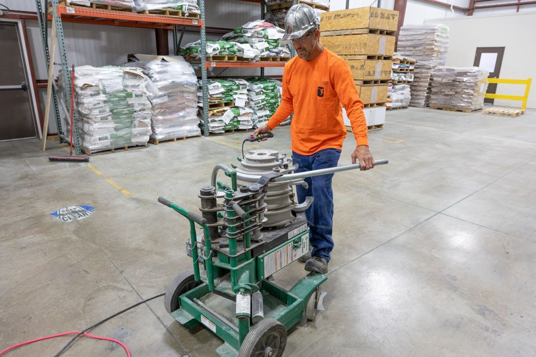 A man is pushing a cart with a machine on it in a warehouse.