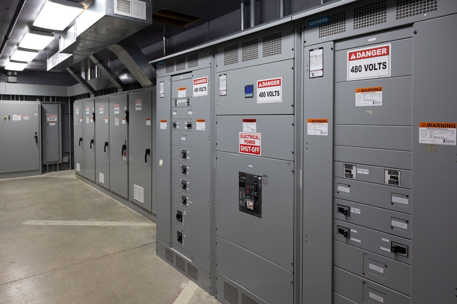 A row of electrical panels with warning signs on them