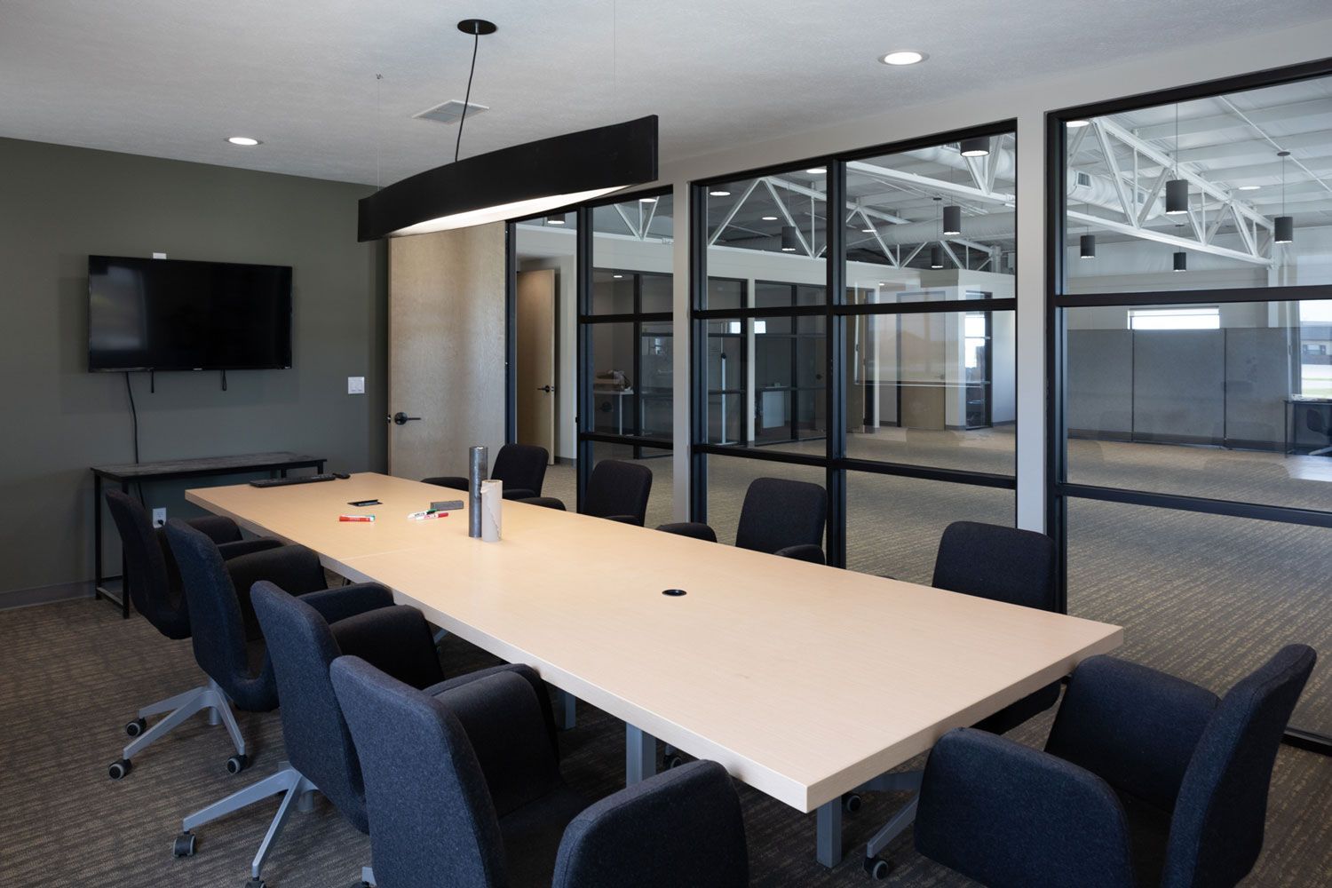 A conference room with a long table and chairs and a flat screen tv.